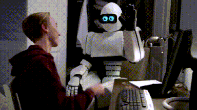 A GiF of a young man sitting in front of a computer and high-fiving a robot.