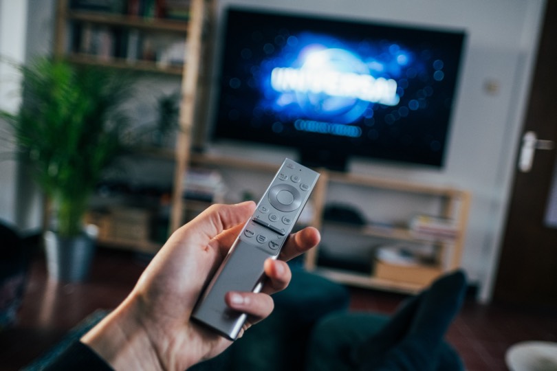 Person holding a remote in front of a TV