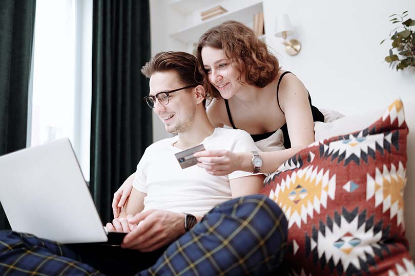Um homem e uma mulher a sorrir enquanto fazem compras online